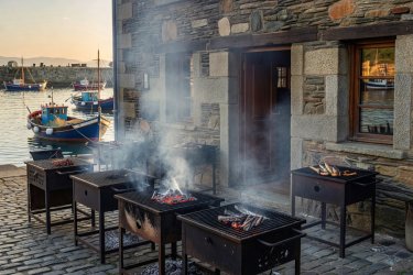 Outdoor charcoal ember grills smoking outside a stone restaurant in Getaria Basque Country